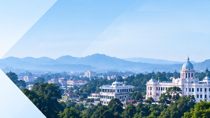 View of a Tripura town with green hills and a white palace-style building